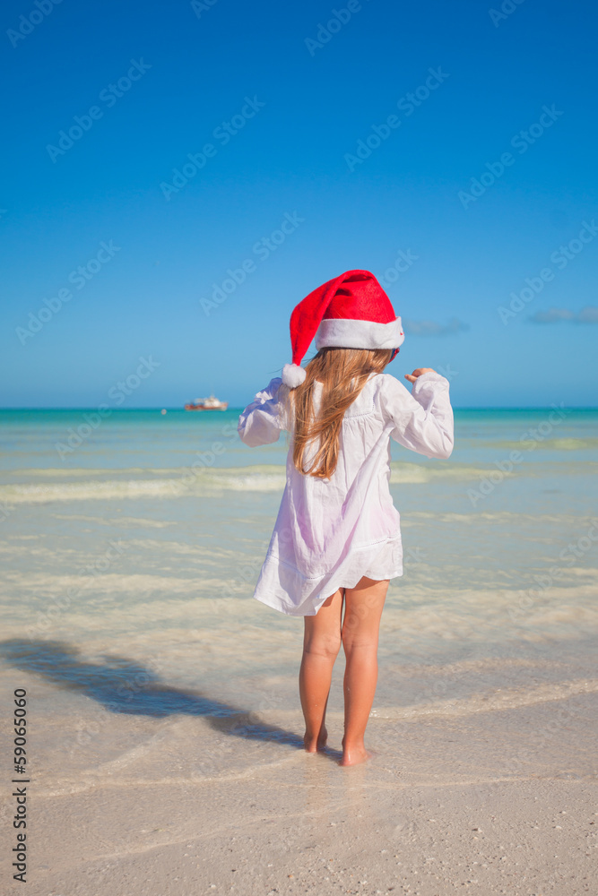 Back view of Little cute girl in red hat santa claus on the