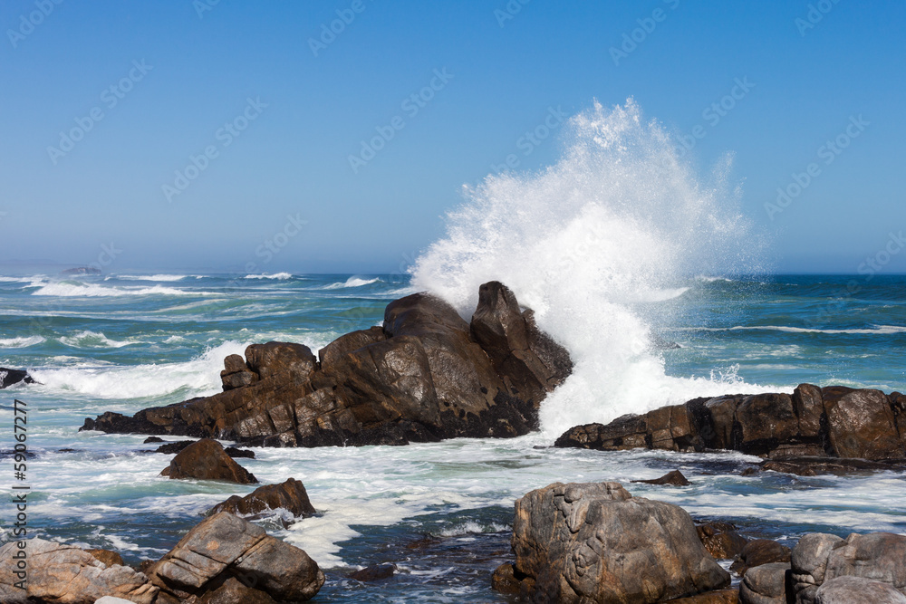 Fototapeta premium Waves crashing against boulders