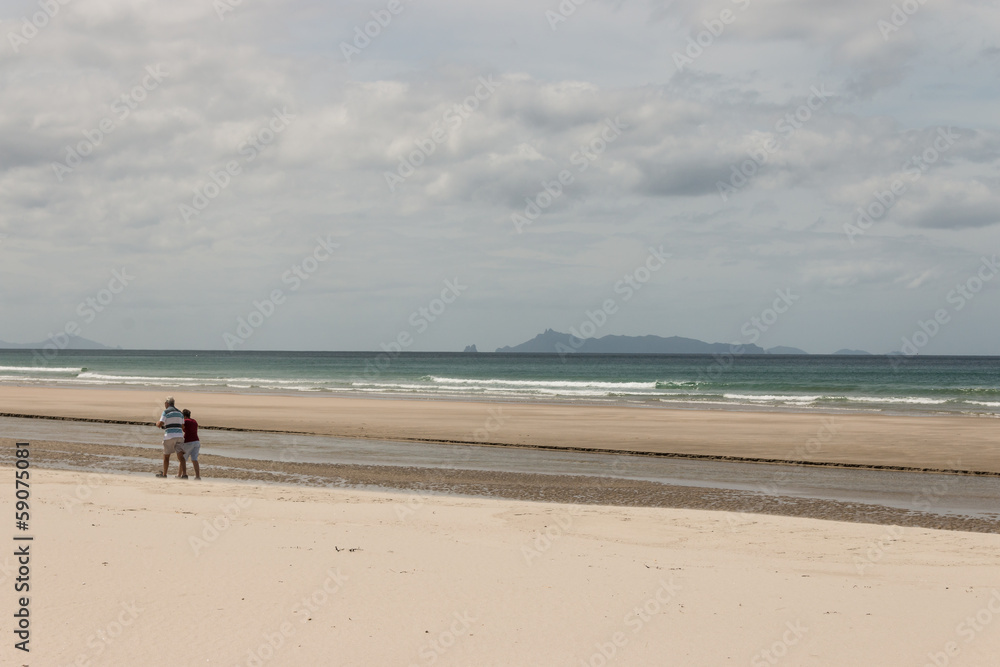 retired couple walking on Pakiri Beach