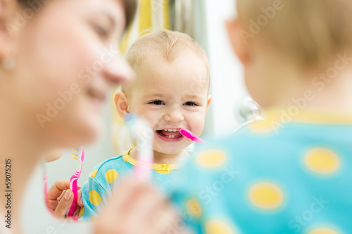 mother teaches baby brushing teeth