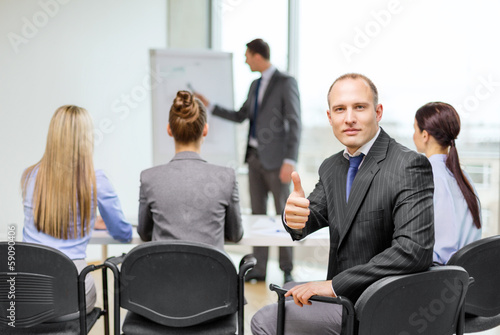 businessman with team showing thumbs up in office