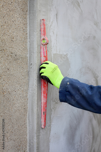 Worker control styrofoam insulation of wall with level tool photo