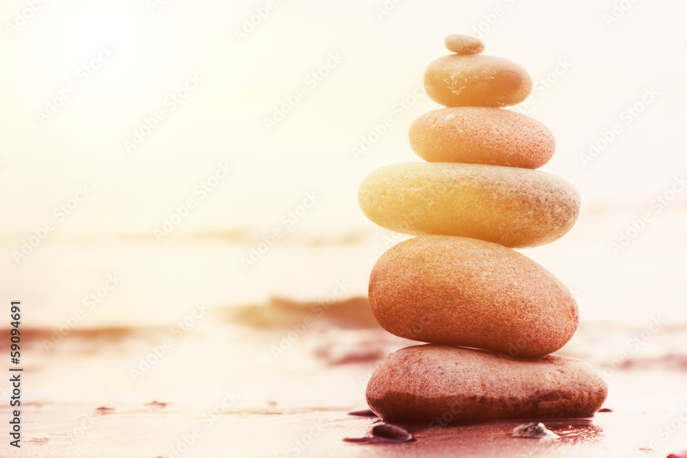 Stones pyramid on sand symbolizing zen, harmony, balance - obrazy, fototapety, plakaty 