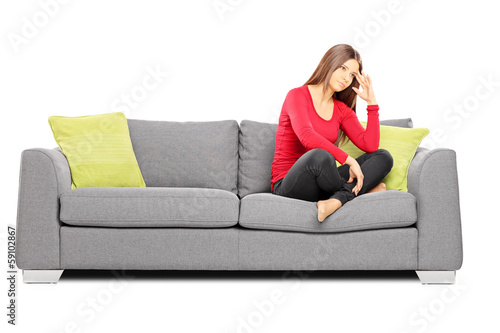 Sad young female sitting on a sofa photo