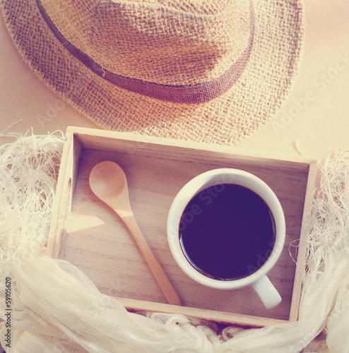 Straw hat with black coffee and spoon on wooden tray, retro filt photo