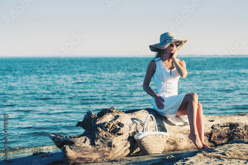 Young woman wearing white dress relaxing at the beach.