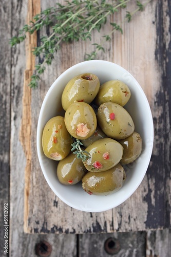 Green olives with thyme on a wooden table
