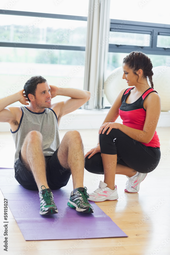 Female trainer looking at man do abdominal crunches Female trainer looking at man do abdominal crunches