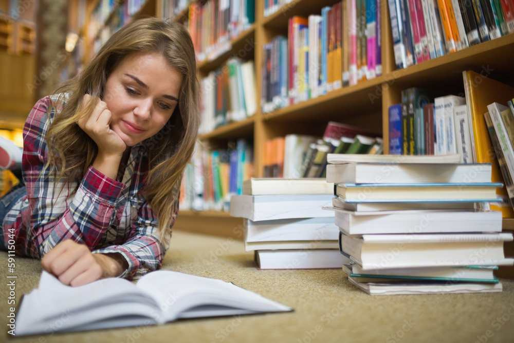 Young happy student lying on library floor reading book Young happy student lying on library floor reading book