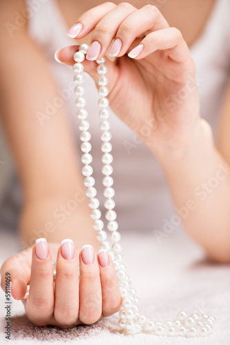 Beautiful woman's nails with french manicure and pearls