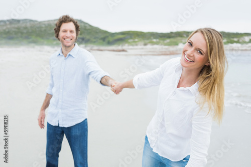 Smiling casual couple holding hands at beach © lightwavemedia
