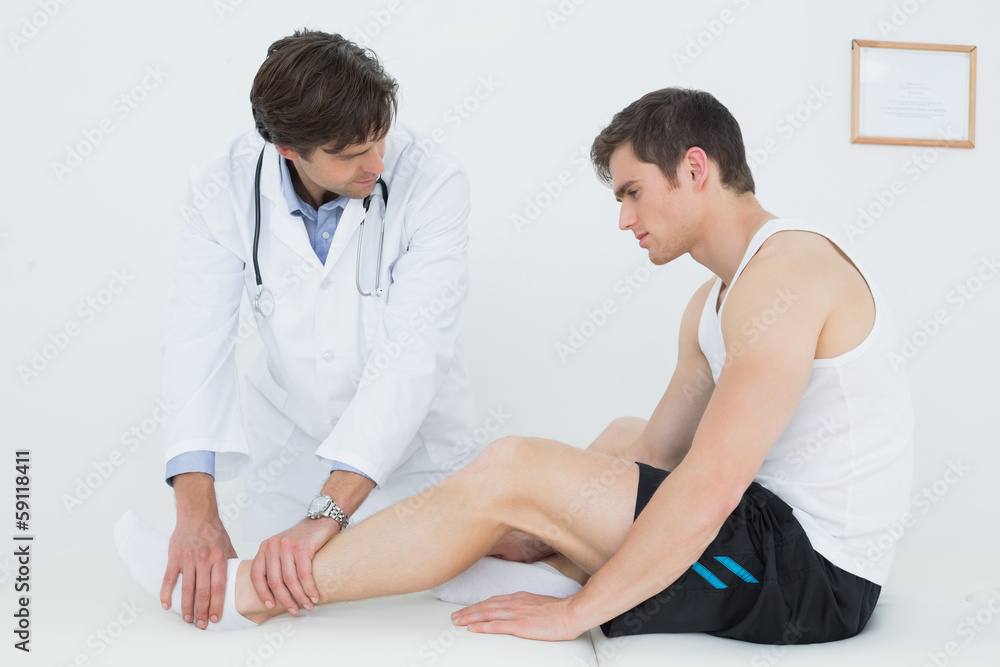 Side view of a young man getting his ankle examined Side view of a young man getting his ankle examined