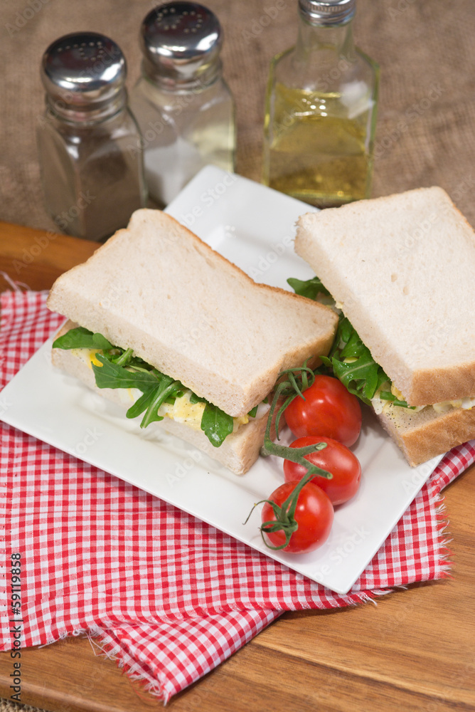 Fresh egg and rocket on white sandwich in rustic kitchen setting