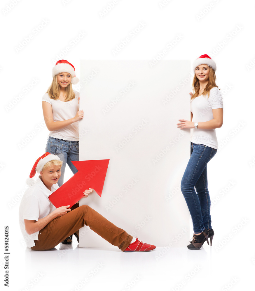 Three happy teenagers in Christmas hats pointing on a banner Three happy teenagers in Christmas hats pointing on a banner