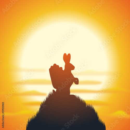 Hase mit Ostereiern auf Grashügel vor Sonnenaufgang