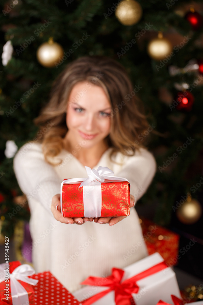 Beautiful woman with presents near the Christmas tree