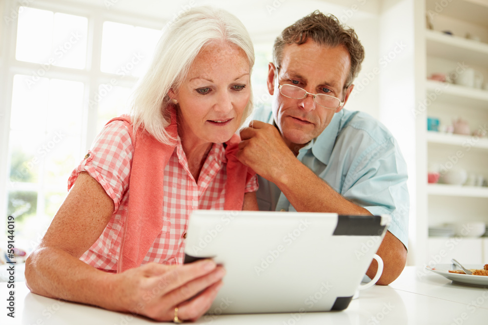Smiling Middle Aged Couple Looking At Digital Tablet Smiling Middle Aged Couple Looking At Digital Tablet