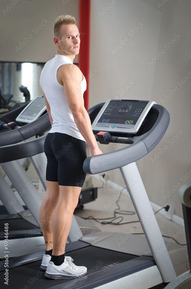 Blond young man standing on treadmill Blond young man standing on treadmill