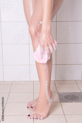 young woman washing legs in the shower