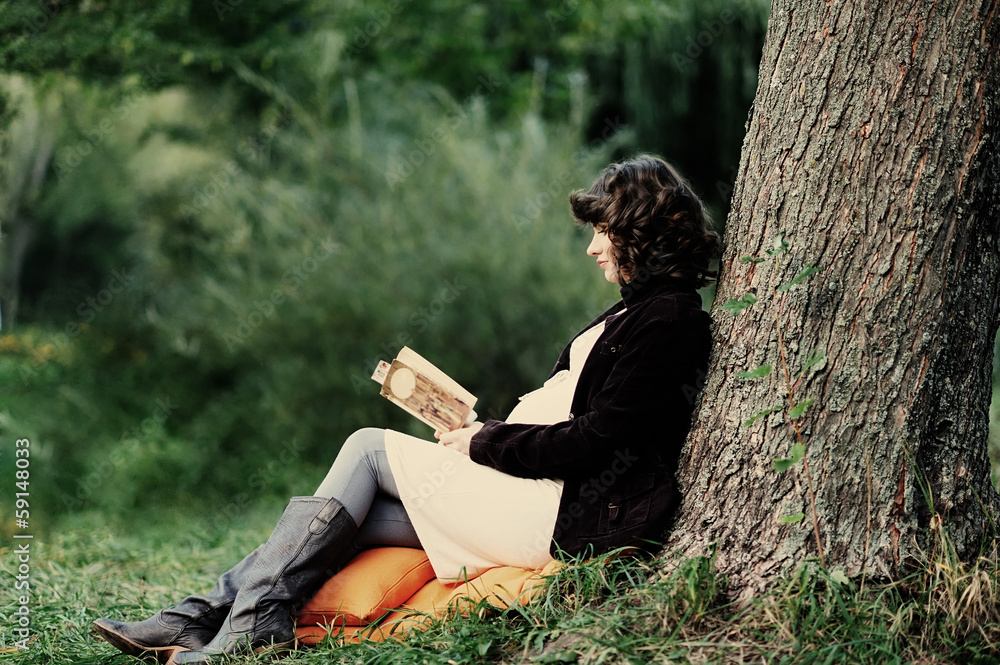 Happy young pregnant woman reading a book Happy young pregnant woman reading a book