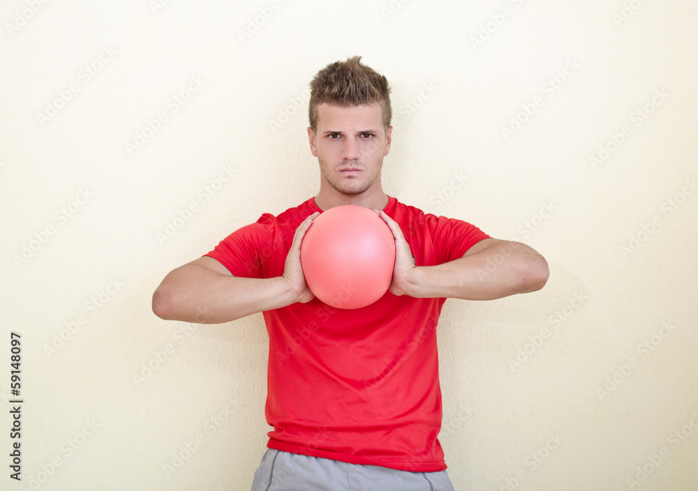 Young man holding exercise ball in his hands