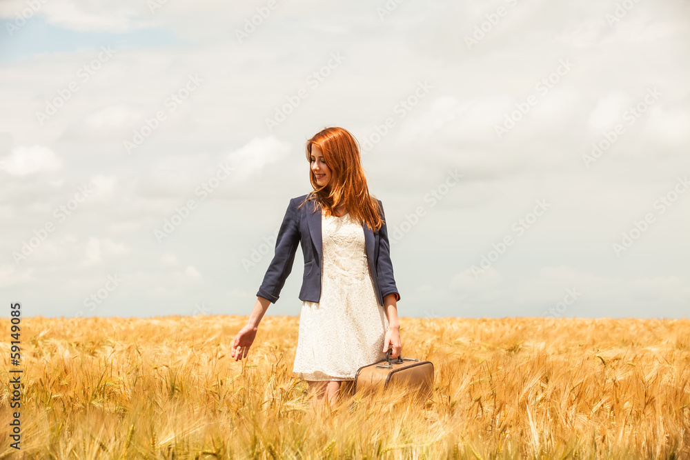 Redhead girl with suitcase at spring wheat field. Redhead girl with suitcase at spring wheat field.