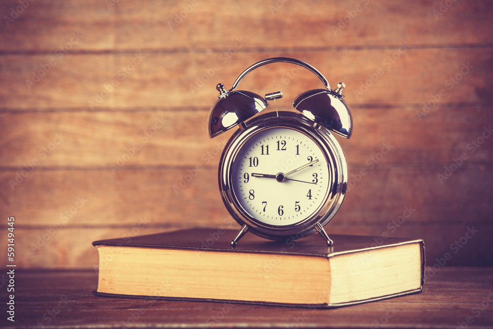 Alarm clock and book. Photo in old color image style. Alarm clock and book. Photo in old color image style.