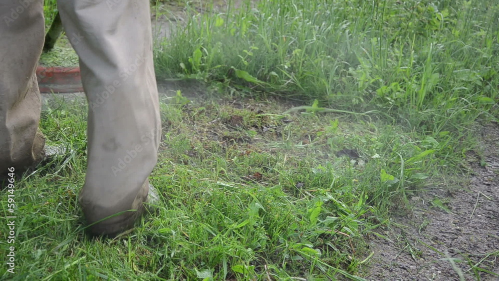 man in wet pants with trimmer takes care of wet grass after rain man in wet pants with trimmer takes care of wet grass after rain