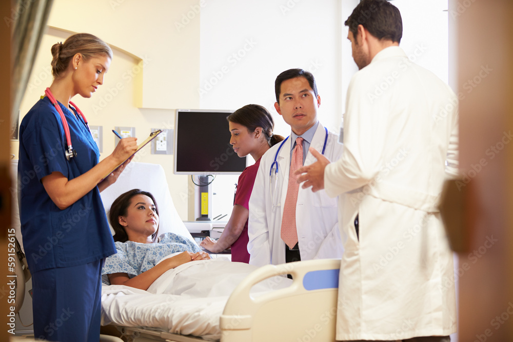 Medical Team Meeting Around Female Patient In Hospital Room Medical Team Meeting Around Female Patient In Hospital Room