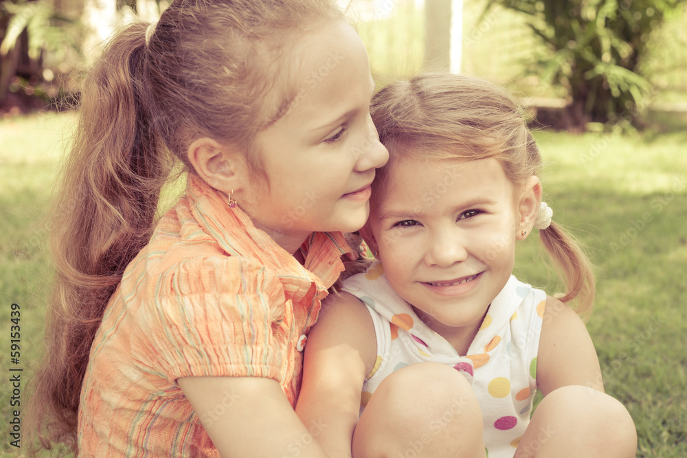 two happy little girls playing in the park in the day time two happy little girls playing in the park in the day time