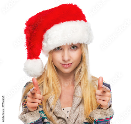 Portrait of happy teenage girl in santa hat pointing in camera