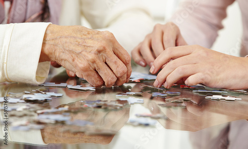 Old hands solving jigsaw puzzle