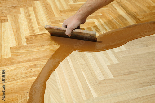Home renovation varnishing oak parquet floor worker hand, brush