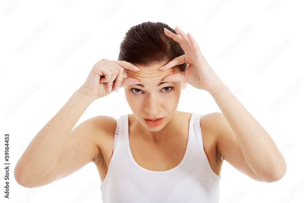 Young beautiful woman is checking her wrinkles on forehead. Young beautiful woman is checking her wrinkles on forehead.