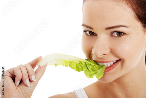 Young beautiful woman eating lettuce.