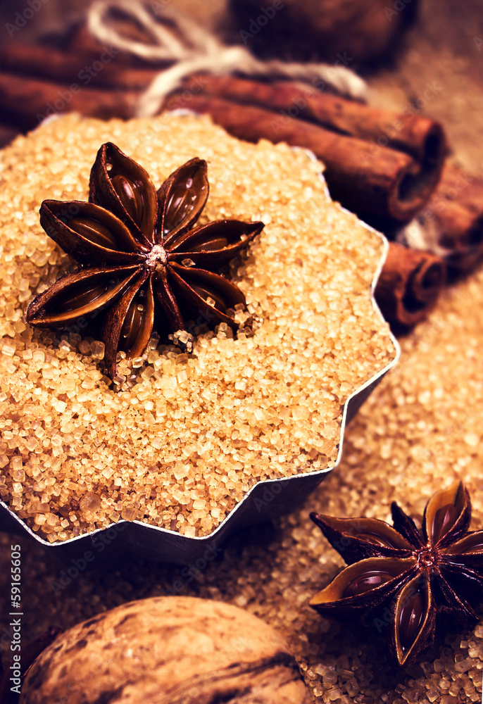 Cinnamon sticks and star anise on cane sugar on wooden backgroun