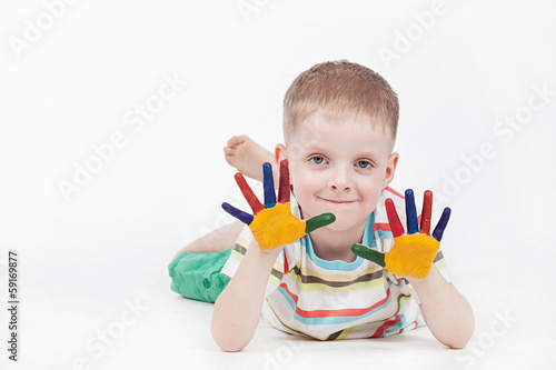 smiling boy with hands in paint on a white background