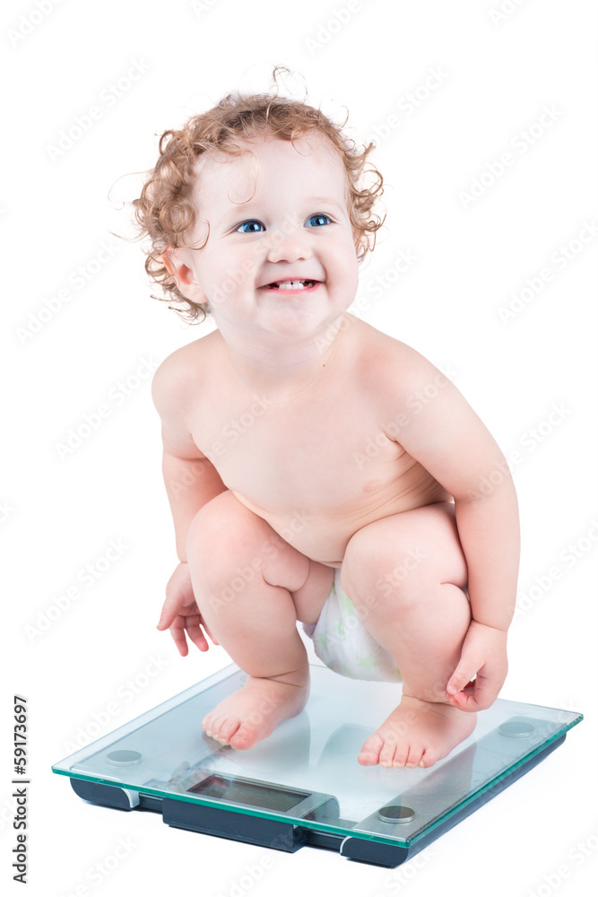 Happy laughing baby watching her weight on a scale, isolated Happy laughing baby watching her weight on a scale, isolated