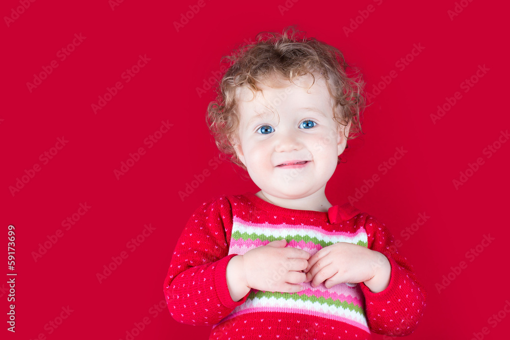 Happy smiling baby girl wearing a red Christmas jacket