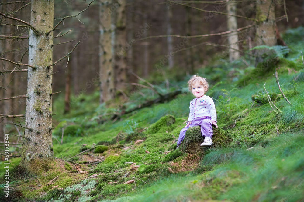 Sweet curly baby girl playing in a beautiful pine wood forest in Sweet curly baby girl playing in a beautiful pine wood forest in