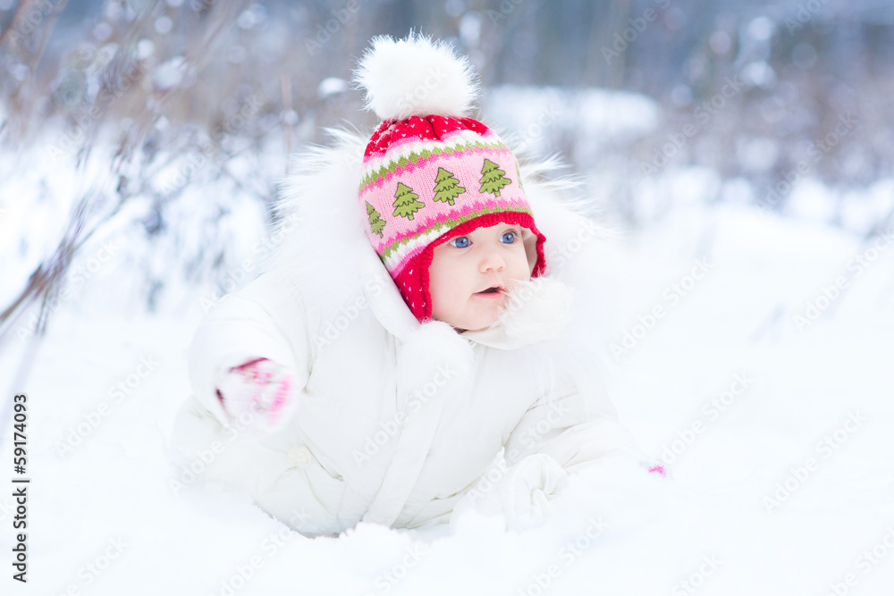 Sweet little baby girl with beautiful blue eyes playing in snow