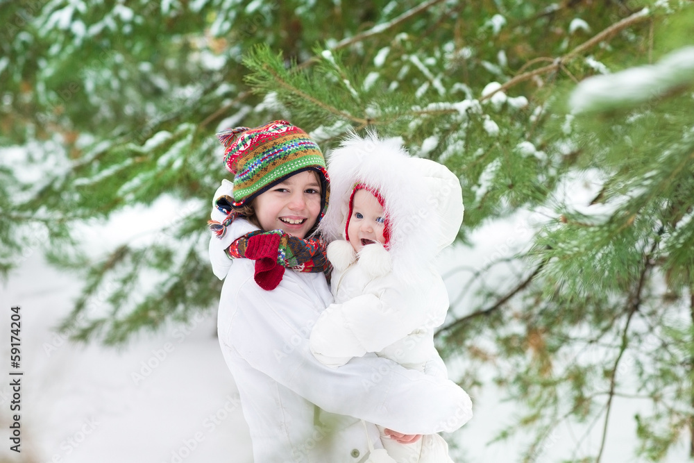 Cute boy hugging his baby sister in a beautiful winter park Cute boy hugging his baby sister in a beautiful winter park