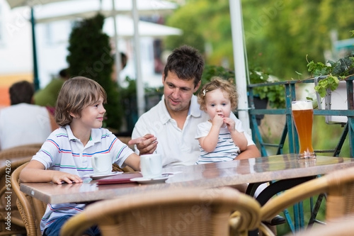 Young father relaxing in an outside cafe with his children