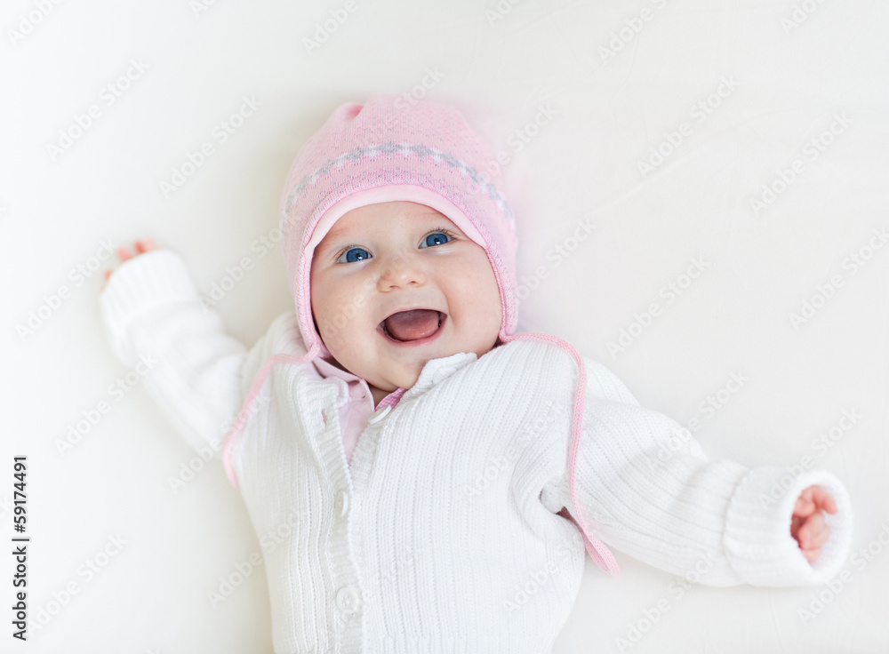 Laughing baby girl in a white knitted sweater and a warm hat Laughing baby girl in a white knitted sweater and a warm hat