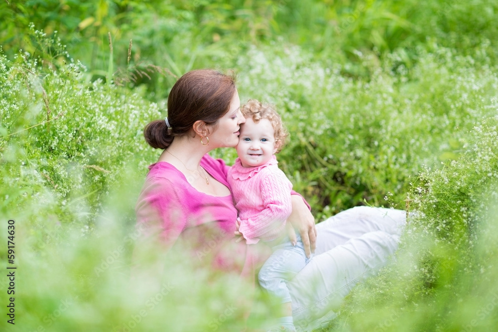 Pregnant mother and her baby daughter relaxing in the garden Pregnant mother and her baby daughter relaxing in the garden
