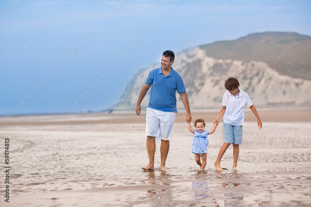 Active father playing with his baby daughter and son on a beach Active father playing with his baby daughter and son on a beach