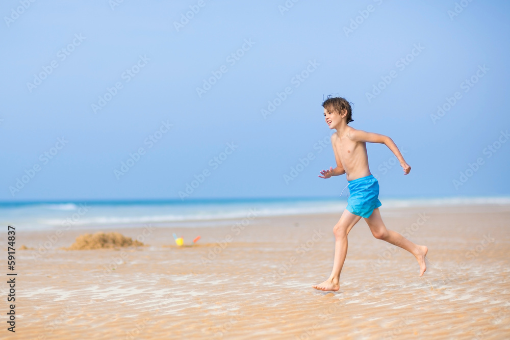 Happy young boy running on a beautiful tropical beach