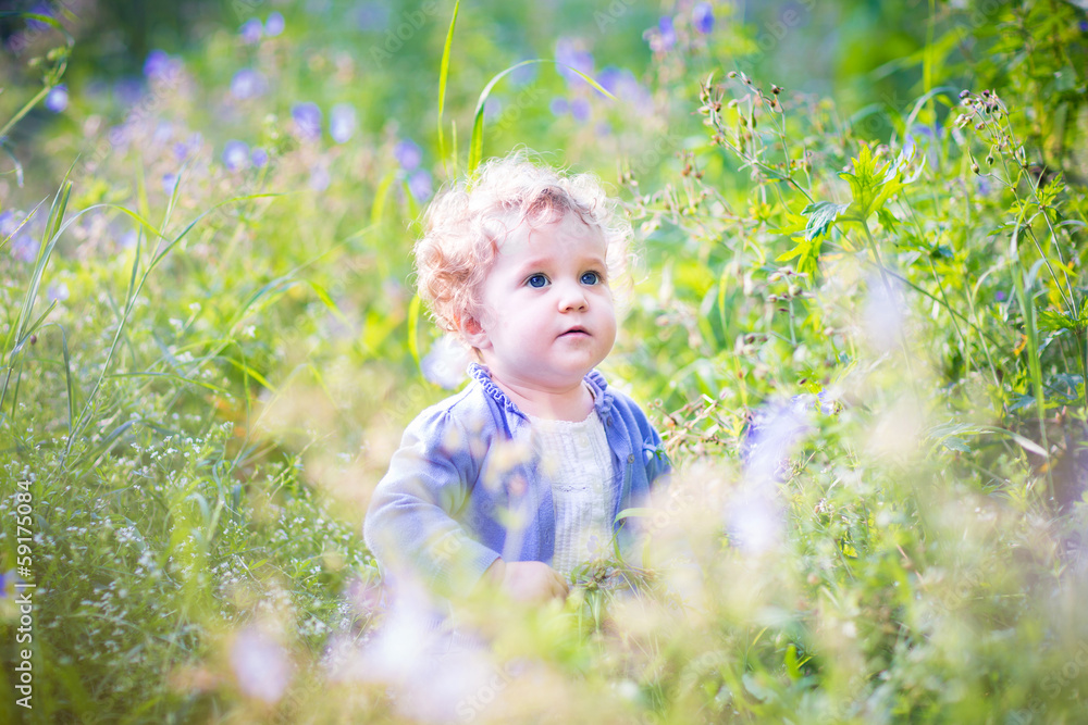 Adorable baby girl playing in a garden on a sunny summer day