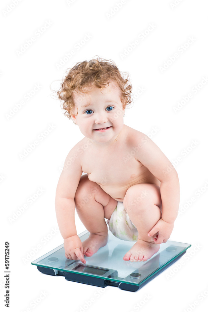 Cute baby girl on a weight scale, isolated on white