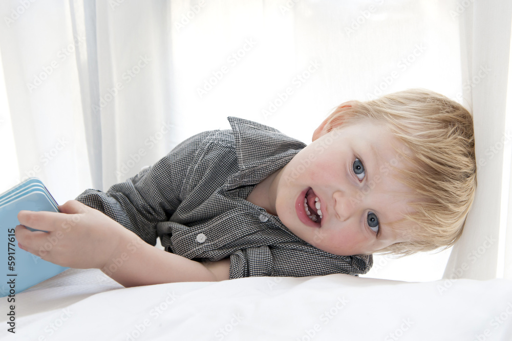 Fototapeta premium Cute little child lying on bed with book